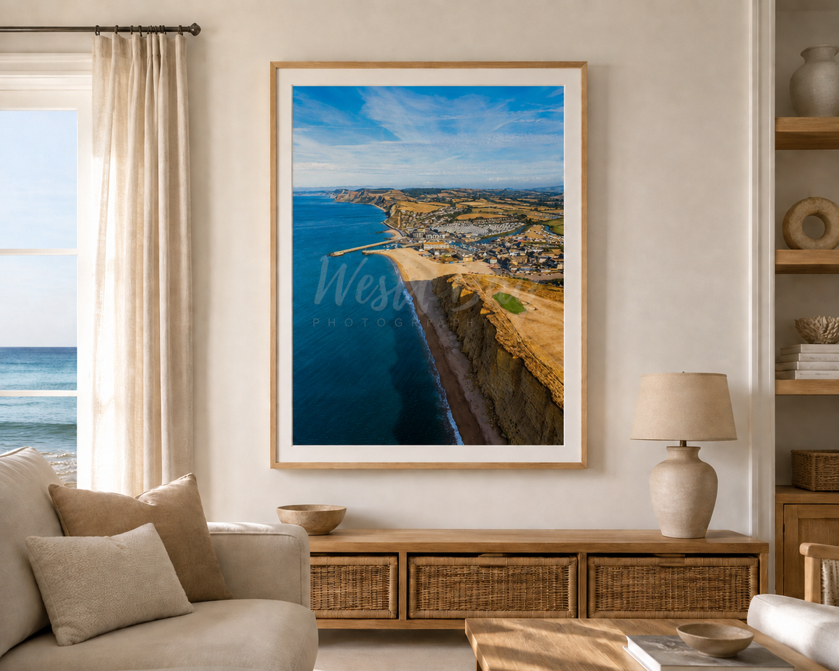 August Morning West Bay aerial photograph displayed in an oak frame in a coastal living room
