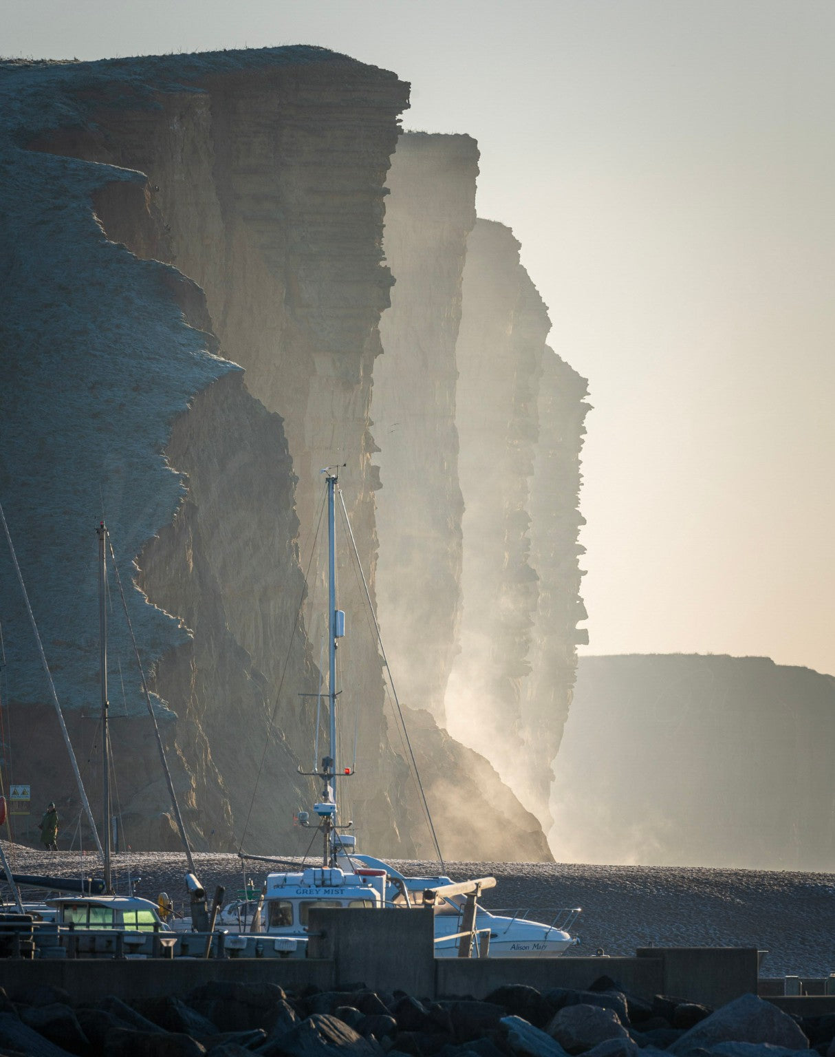 Layered view of East Cliff with harbour boats at West Bay, Dorset