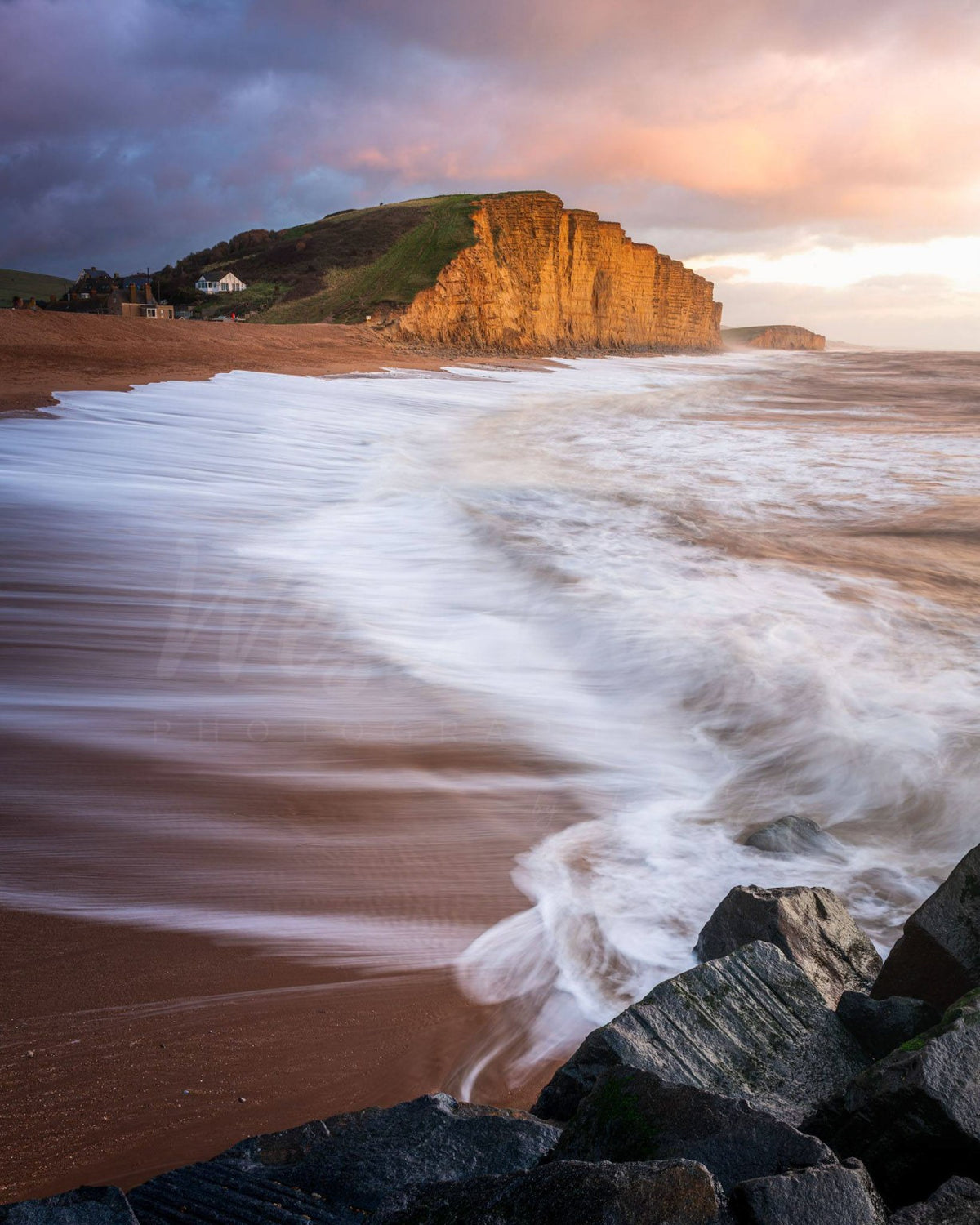 Long exposure waves sweeping across East Beach beneath East Cliff at West Bay, Dorset