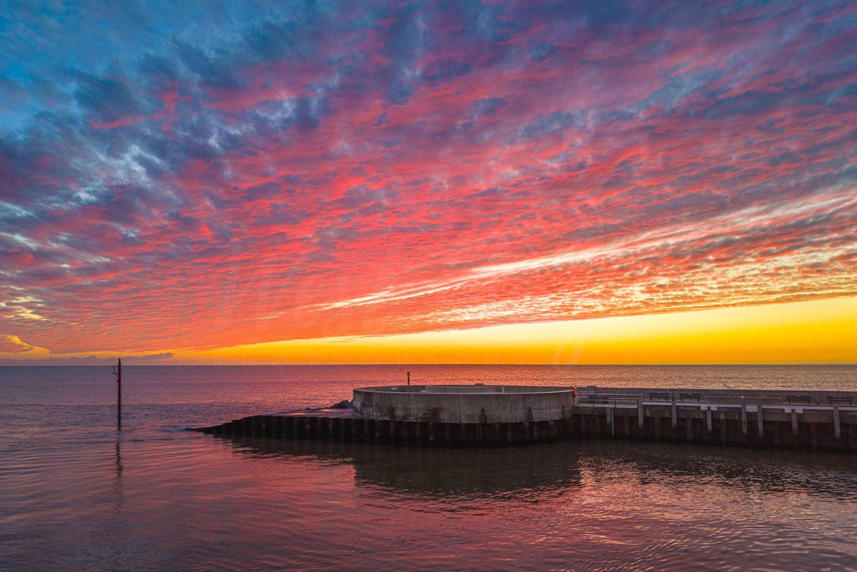 Vivid red and orange sunset above West Bay harbour entrance, Dorset