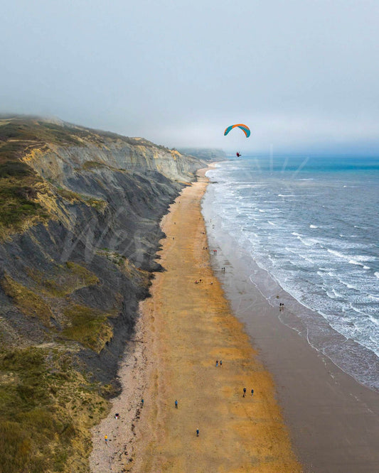 Jurassic Drift – paraglider above Charmouth beach and cliffs on the Jurassic Coast, Dorset