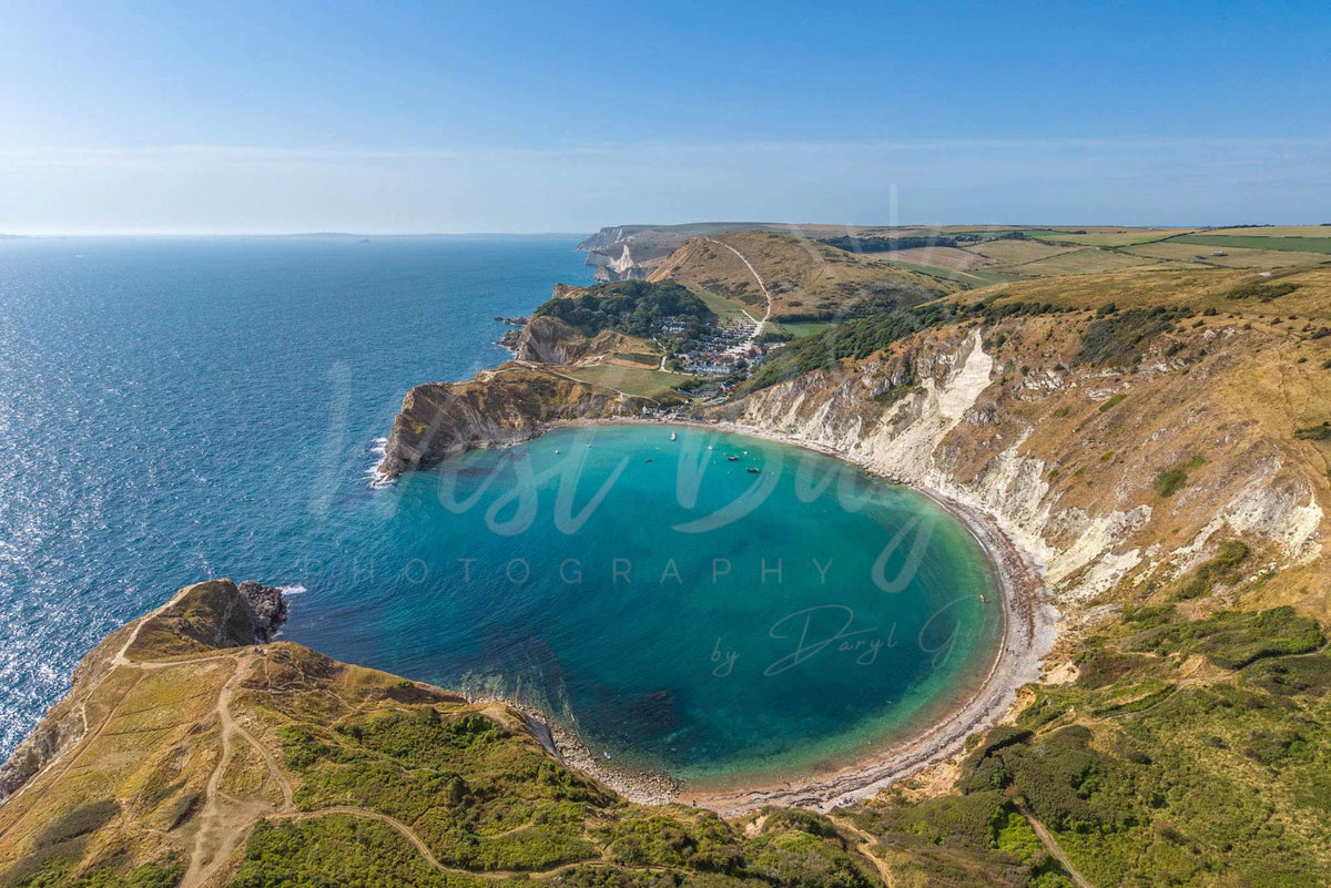 Aerial view over the turquoise water and chalk cliffs of Lulworth Cove, Dorset