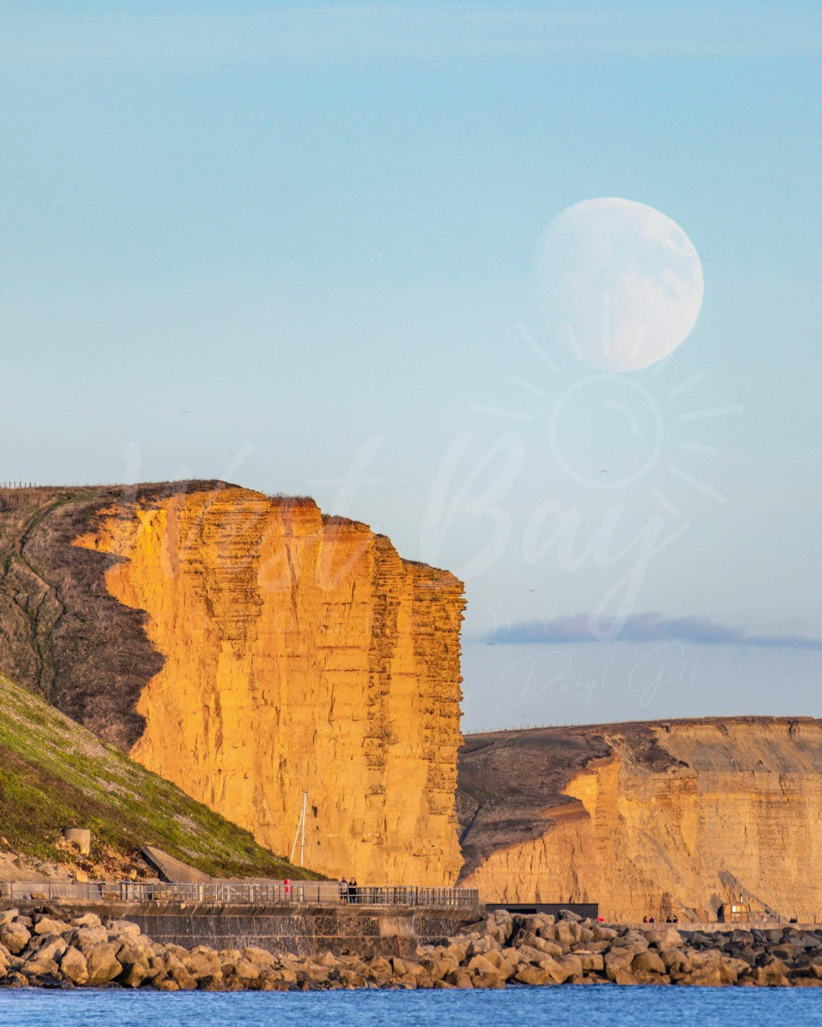 Close view of the moon above the golden East Cliff at West Bay, Dorset