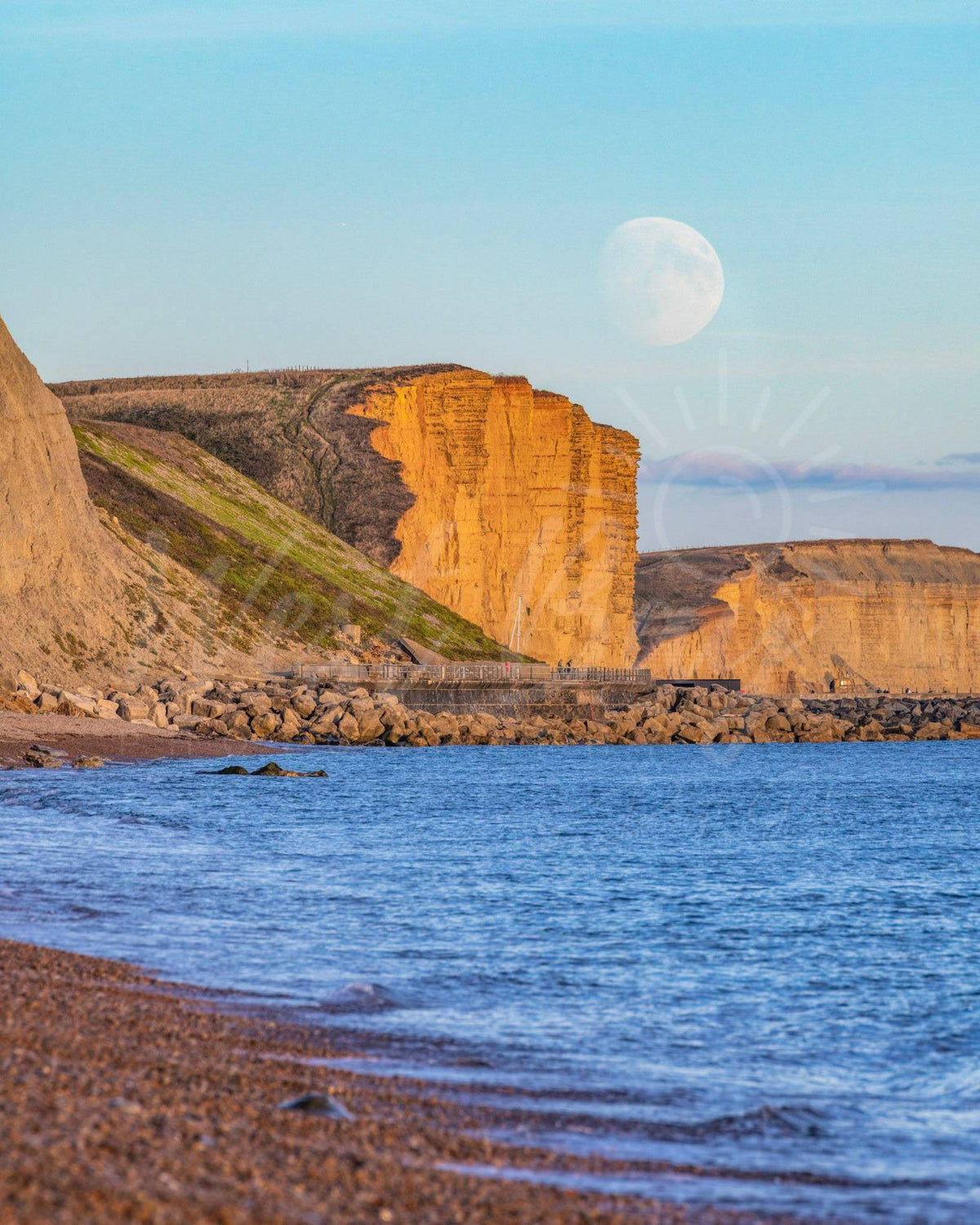 Moon above East Cliff at West Bay viewed across the sea from Eype Beach, Dorset